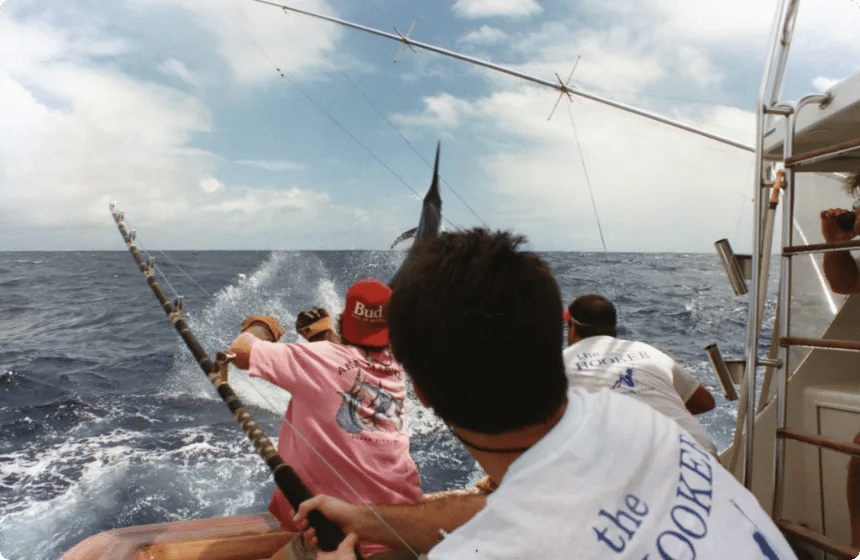 Anglers working a billfish off the cockpit of a sportfish convertible as a marlin jumps behind the boat.