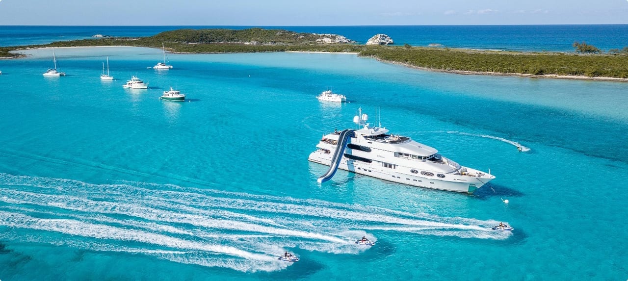 Luxury superyacht anchored in the pristine turquoise shallows of the Exumas, Bahamas with sandbars visible below