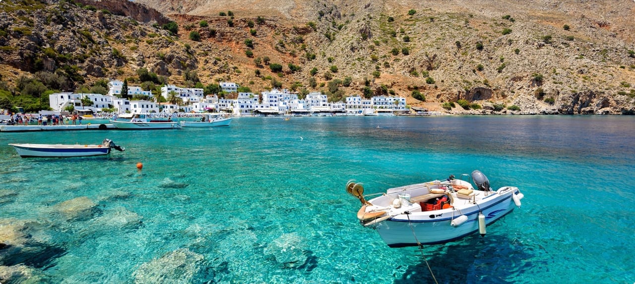 Luxury yacht anchored in a secluded Greek island cove with crystalline water and lush green hillside