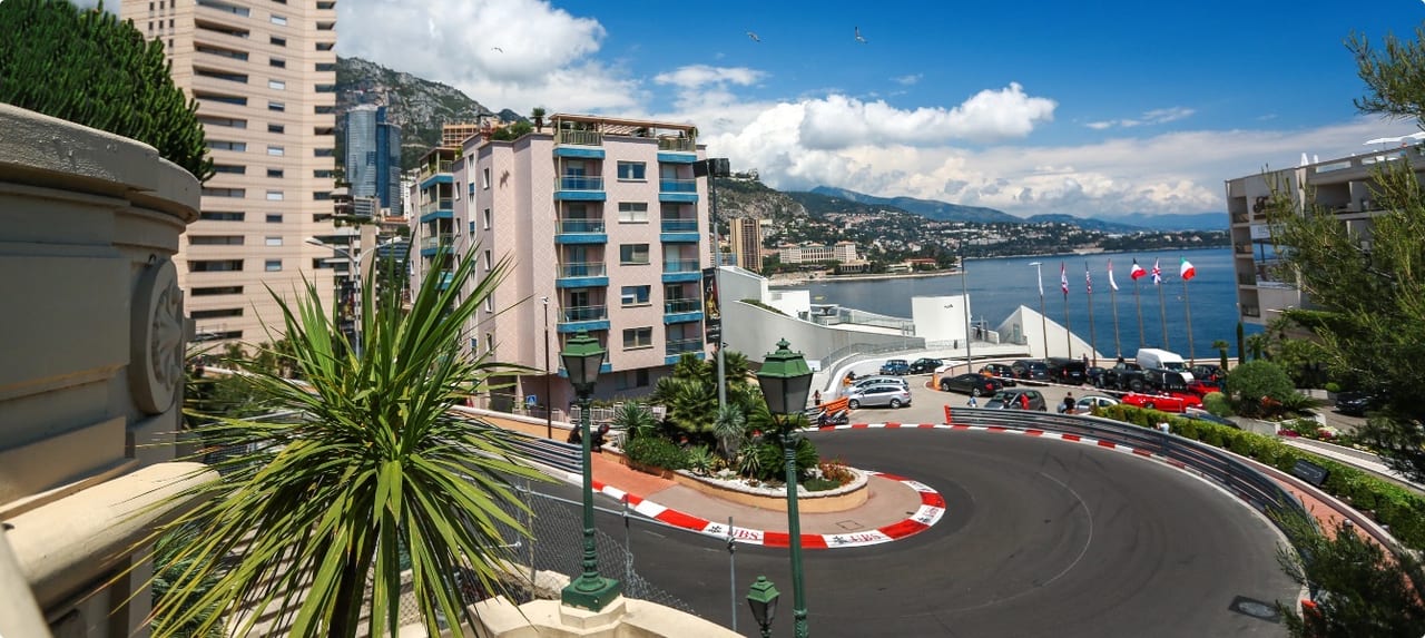 Monaco Grand Prix circuit winding past the harbor with spectator stands and superyachts in the background