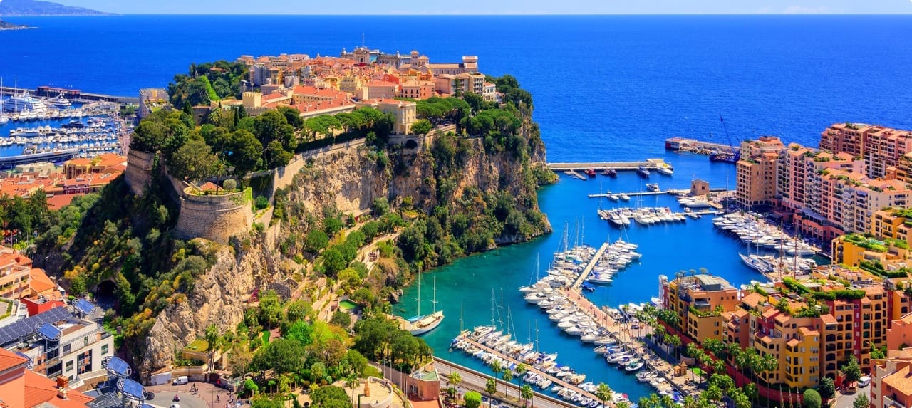 Monte Carlo's famous waterfront promenade lined with palm trees and luxury boutiques overlooking the Mediterranean