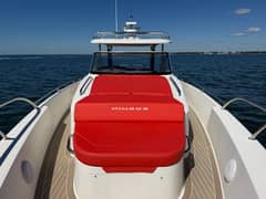 2022 40' 7" Nimbus T-11 - Red cushioned bow seating and sunpad with hardtop and windshield beyond
