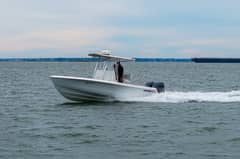 2023 24' 6" Contender 24S - White center console boat with T-top underway on open water