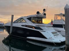 2015 Regal 53 Sport Coupe - Port side profile of a dark-hulled express cruiser docked at a marina