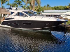 2015 Regal 53 Sport Coupe - Port side profile of a dark-hulled express cruiser moored alongside a dock