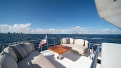 2020 Azimut 50 Flybridge - Exterior deck seating area with cushioned sofas, throw pillows and a varnished table