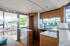2026 Princess F58 - Interior galley with wood cabinetry, countertops and sink beside sliding glass doors