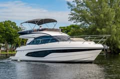 2025 47' 1" Princess F45 - White flybridge motor yacht underway on water, starboard bow view, with person at upper helm