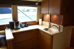 2006 Ocean Yachts 42 Super Sport - Galley countertop with sink, faucet, small appliances and wood cabinets below a window