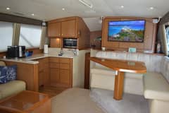 2006 Ocean Yachts 42 Super Sport - Salon interior with dinette seating, wall-mounted television and adjoining galley