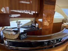 2009 63' 1" Azimut 62 Motor Yacht - Galley with wood cabinetry, cooktop and counter behind a stainless rail