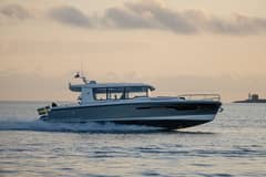 2027 Nimbus Sport Coupe 42 - Gray enclosed-pilothouse motor yacht underway on open water, starboard profile view