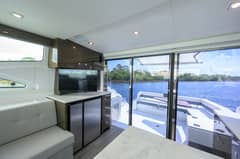 2020 46 Cruisers Cantius - Salon interior with seating, television and counter beside sliding doors to cockpit