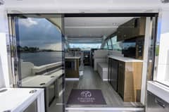 2020 46 Cruisers Cantius - View through open glass doors into salon with seating, galley and television
