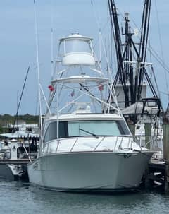 2022 Viking 44 Sport Coupe - Bow view of a white sportfishing yacht with tuna tower, moored at a dock