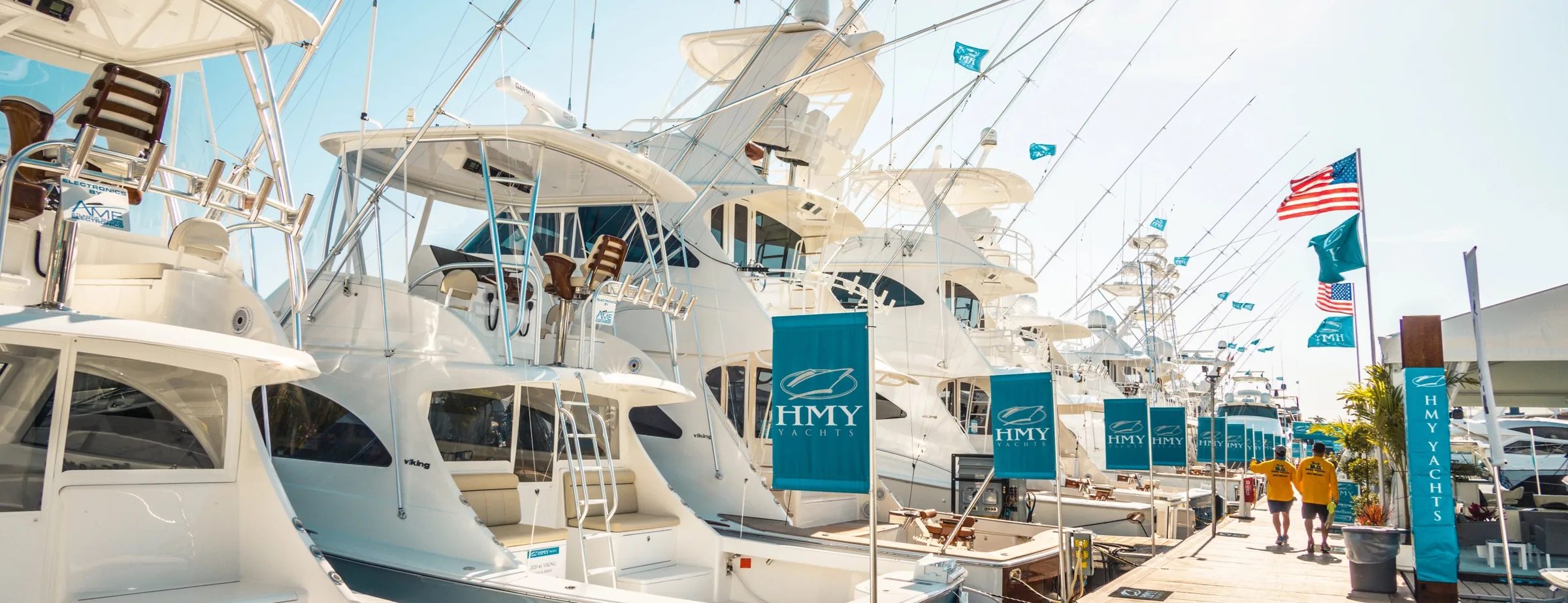 HMY sportfish yacht display at a Florida boat show with HMY banners between hulls