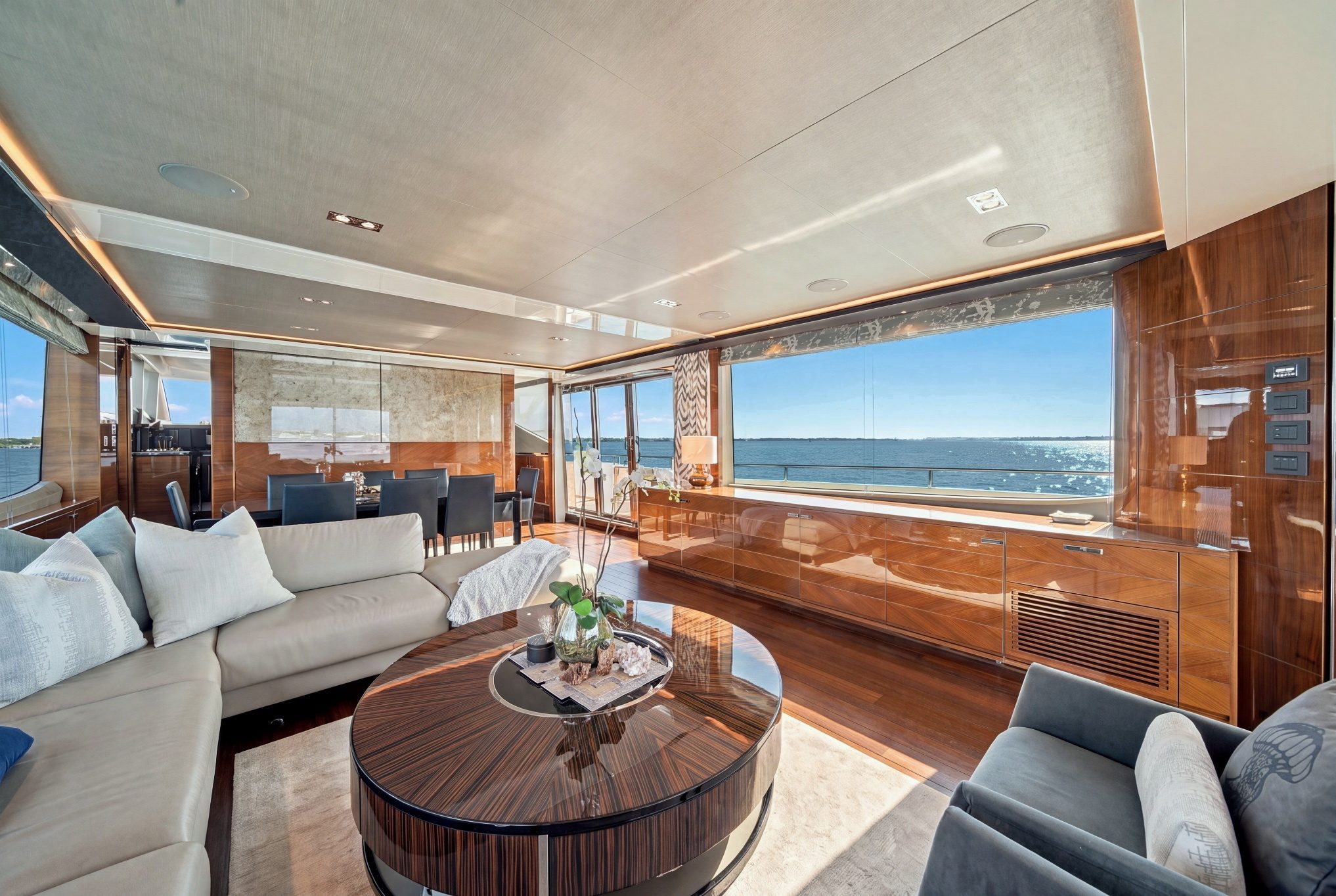 2017 Princess Yachts 88 Flybridge - Salon with sectional sofa, round coffee table and dining table forward