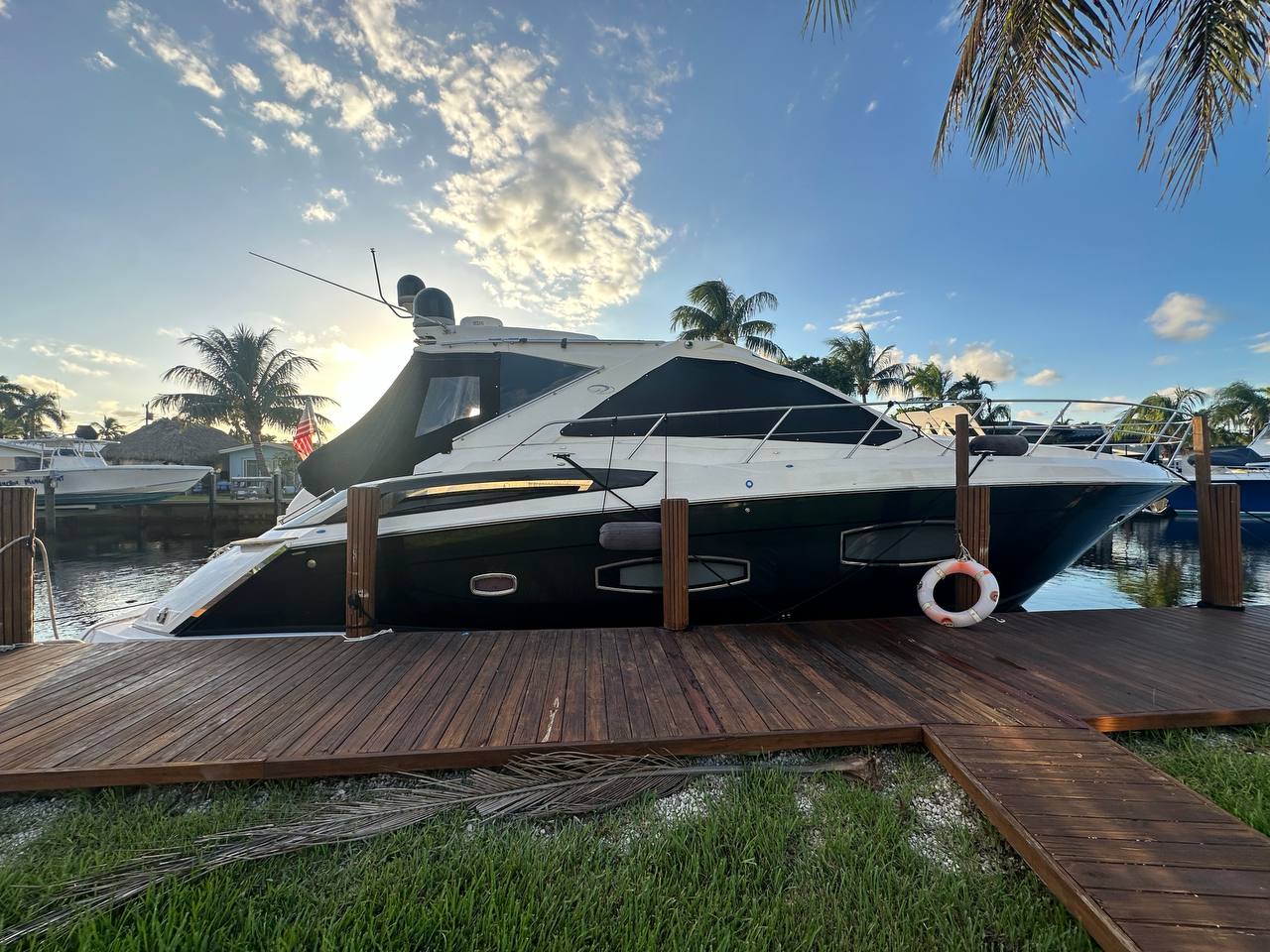 2015 Regal 53 Sport Coupe - Profile view of a dark-hulled motor yacht moored alongside a wooden dock