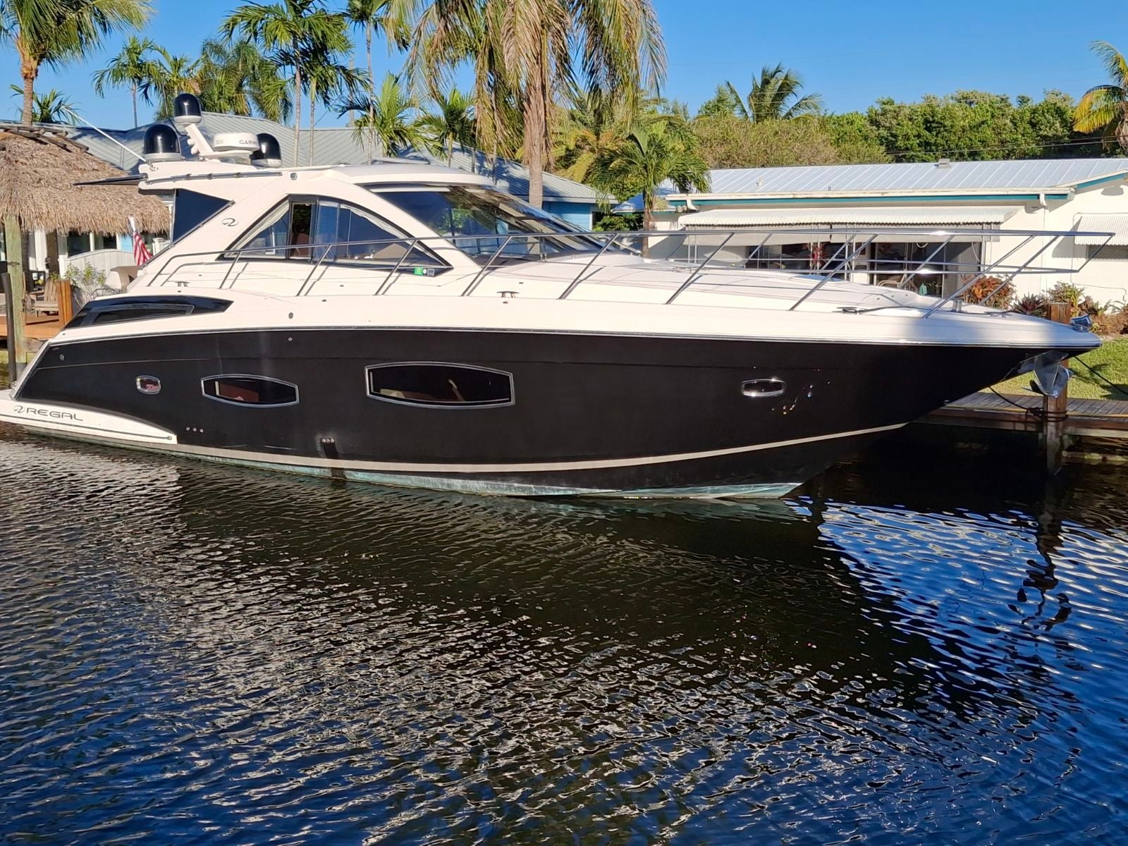 2015 Regal 53 Sport Coupe - Port side profile of a dark-hulled express cruiser moored alongside a dock