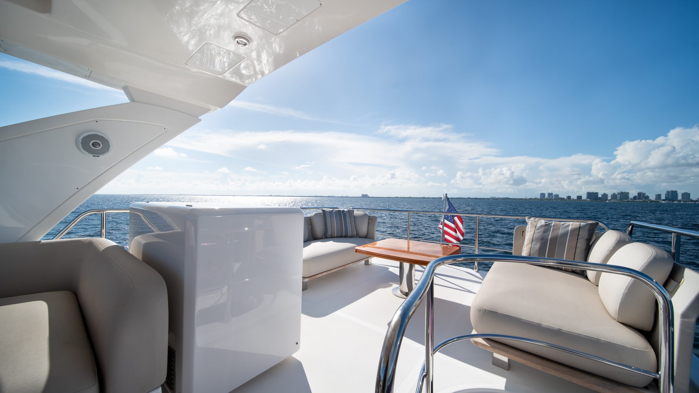 2020 Azimut 50 Flybridge - Flybridge seating area with cushioned settees, loose pillows and a varnished table