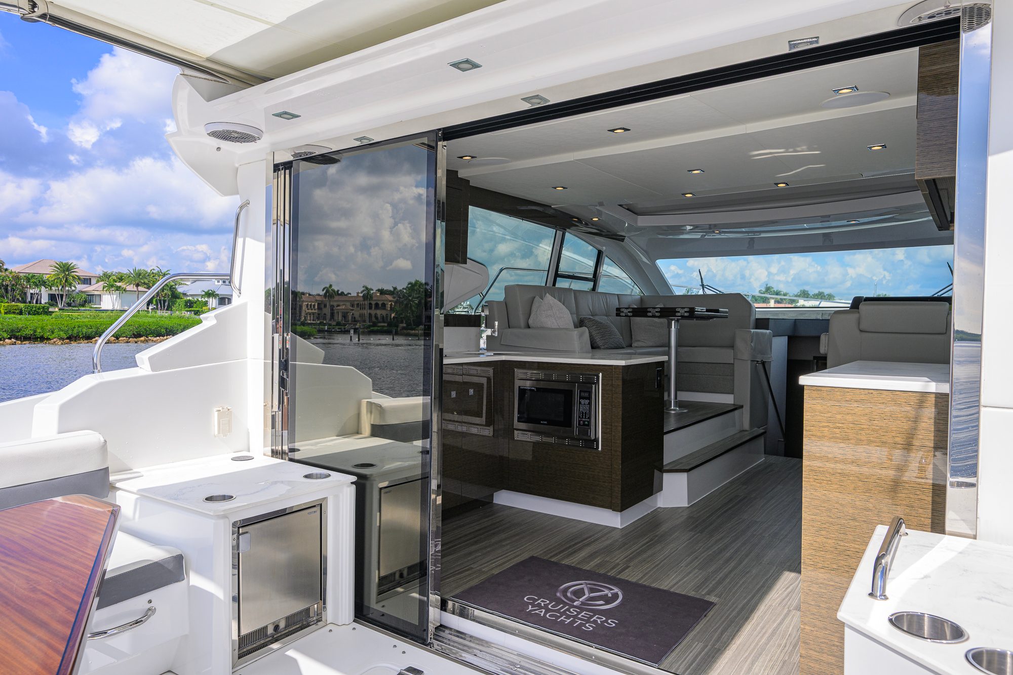 2020 46 Cruisers Cantius - Open sliding glass door between cockpit and salon with seating and galley