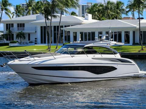 Princess V50 Open express cruiser passing a luxury waterfront estate in Fort Lauderdale.