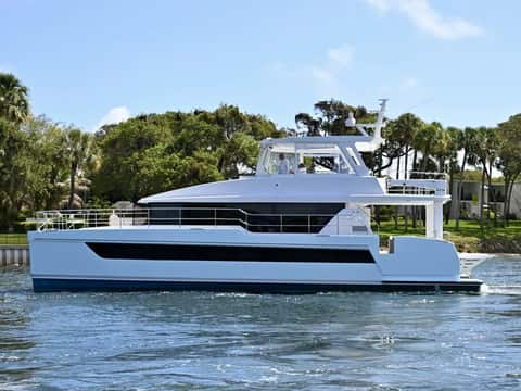 Two Oceans 555 power catamaran on calm Intracoastal water in front of palm trees.
