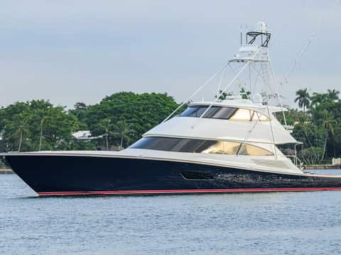 Dark-hull Viking convertible idling along a palm-lined Florida waterway at twilight.