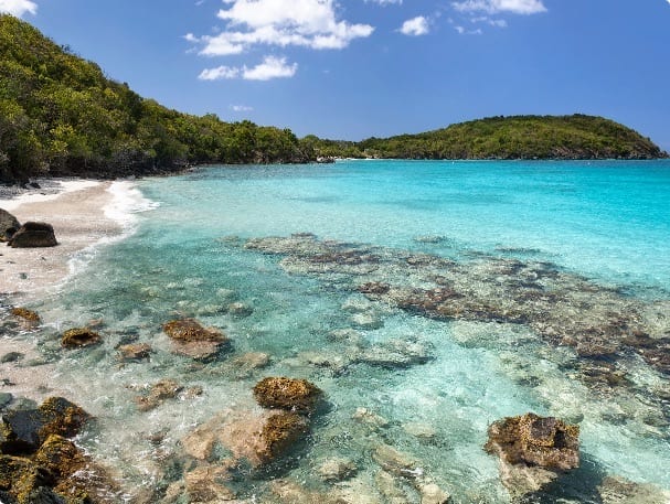 Aerial view of a sheltered USVI bay with yachts at anchor surrounded by green volcanic hillsides