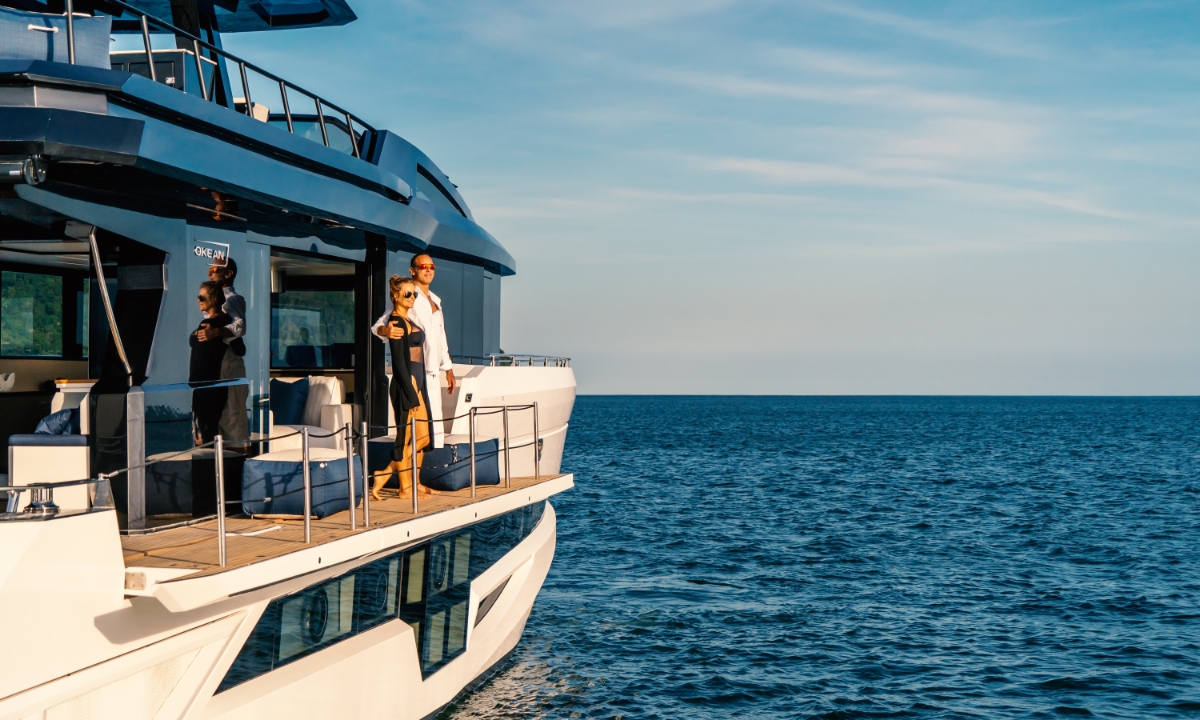 a man and a women standing on the side of the yacht looking out over the ocean