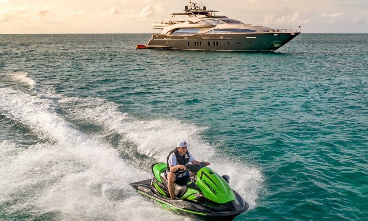 a man on a power toy having some fun next to a yacht