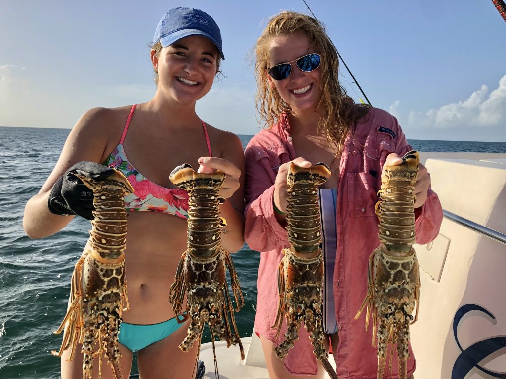 Two ladies holding spiny-lobsters