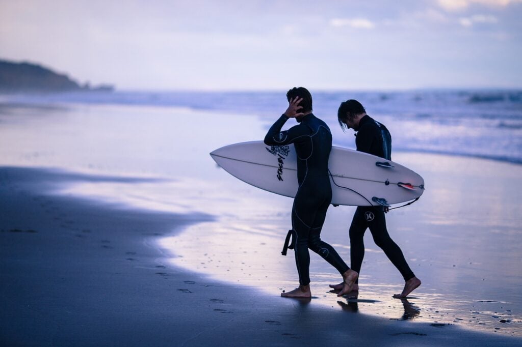 couple on beach with yacht surfboard